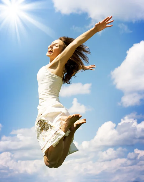 Jeune femme heureuse sautant par-dessus le ciel bleu — Photo