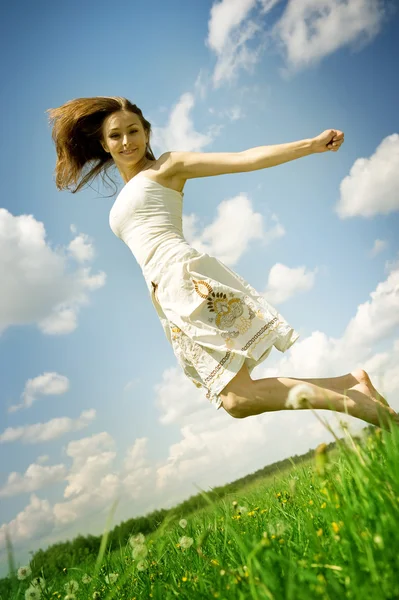 Felice giovane donna saltando sopra il cielo blu — Foto Stock
