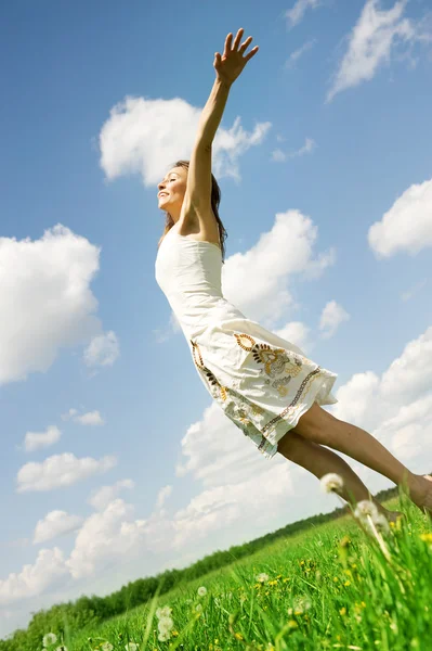 Glückliche junge Frau springt über blauen Himmel — Stockfoto