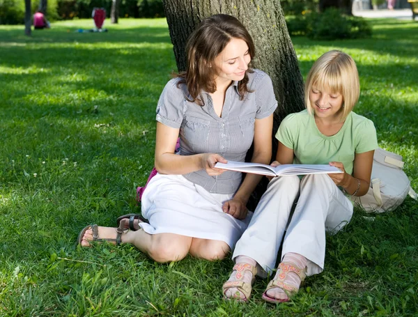 Mãe e filha lendo o livro em um parque. Educação Concep — Fotografia de Stock