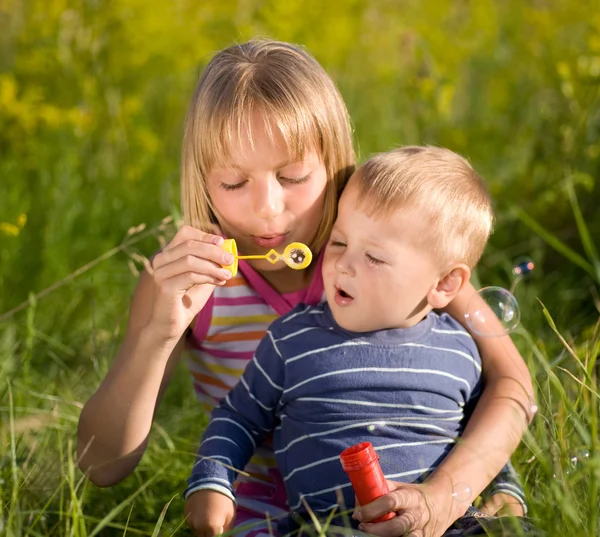 Glad syster och bror blåser såpbubblor — Stockfoto