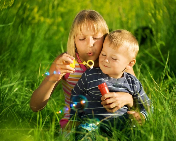 Glad syster och bror blåser såpbubblor — Stockfoto