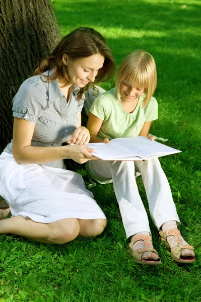 Anya és lánya, olvasta a könyvet, egy parkban. Oktatás klara Stock Fotó