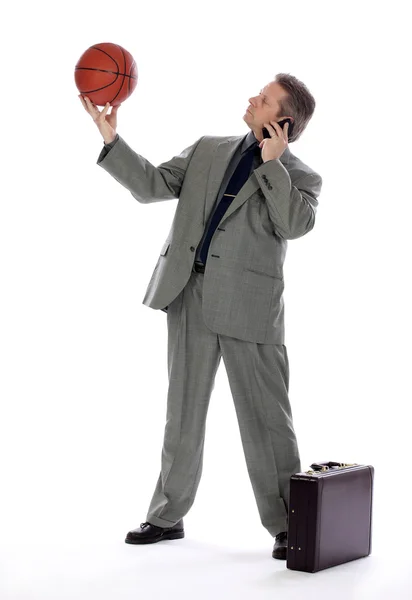 Hombre de negocios sosteniendo una bola de la cesta y teléfono celular — Foto de Stock