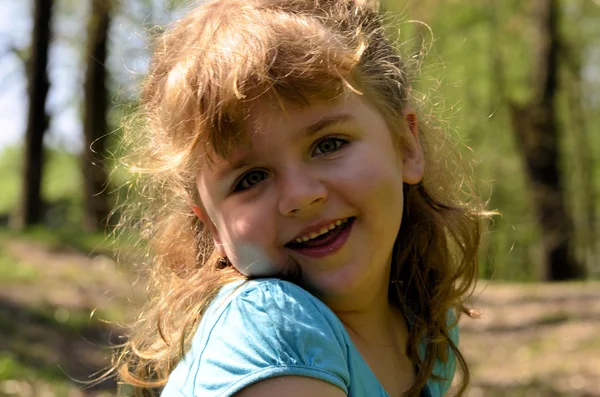 Portræt af en tilfreds lille pige på spil i parken - Stock-foto