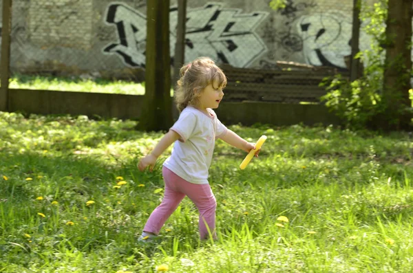 Pikkutyttö juoksee nurmikon poikki — kuvapankkivalokuva
