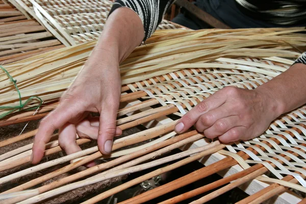 Vrouwelijke handen handmatig mastering rieten stof — Stockfoto