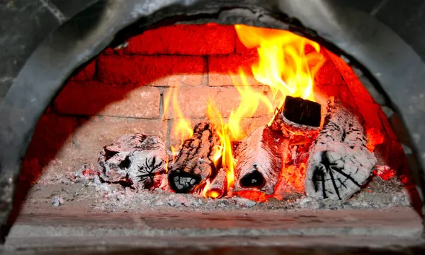 古い家のれんが造りの暖炉で燃える木 ストック画像