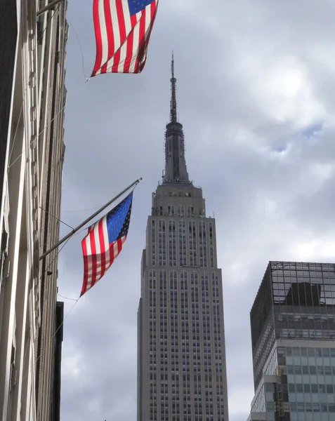 Вид на Эмпайр-стейт-билдинг с двумя американскими флагами Лицензионные Стоковые Изображения