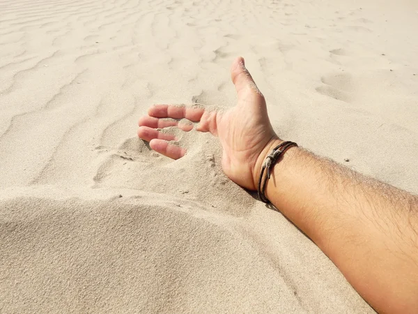 Mano en el juego con la arena en una playa — Foto de Stock