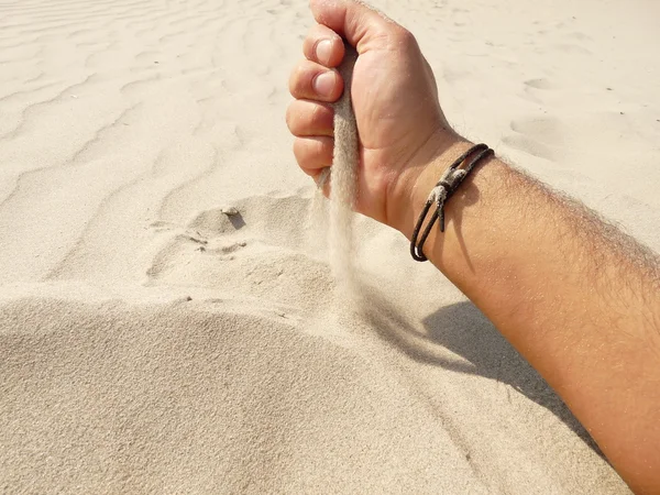 Mano en el juego con la arena en una playa — Foto de Stock