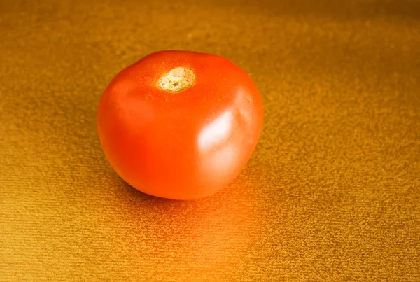 Red tomato on gold — Stock Photo, Image