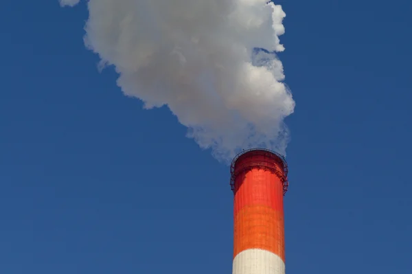 Fumaça pesada de tubo vermelho no fundo do céu azul — Fotografia de Stock