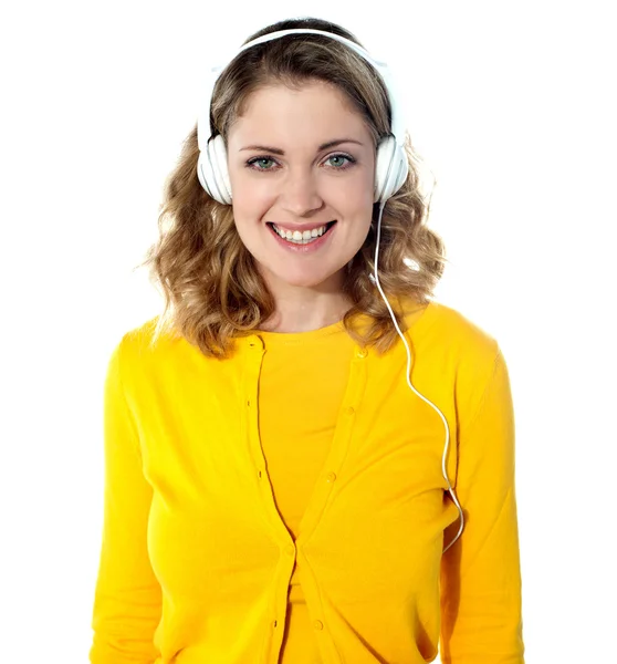 Sorridente giovane donna che ascolta musica in cuffia — Foto Stock