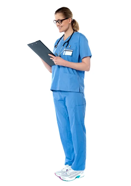 Female surgeon with stethoscope, reading report — Stock Photo, Image