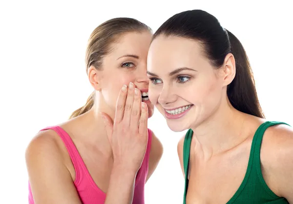 Young beautiful girl whispering secret in her friends ear — Stock Photo, Image