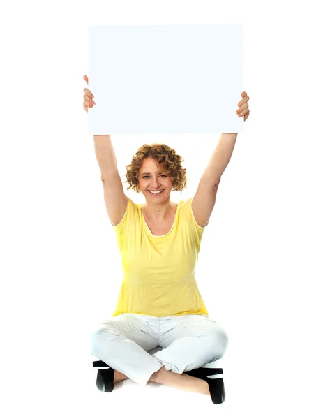 Seated woman holding blank billboard — Stock Photo, Image
