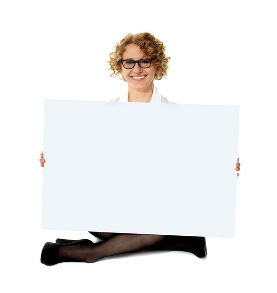Female employee holding white blank banner ad — Zdjęcie stockowe