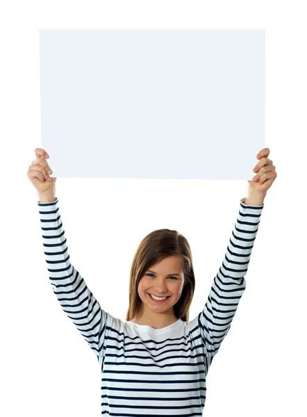 Симпатичная девушка поднимает пустой плакат высоко — стоковое фото