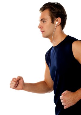 Fit athlete enjoying music in a jogging posture clipart