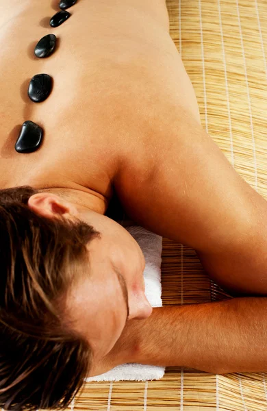 Charmant homme profitant d'un massage aux pierres chaudes — Photo