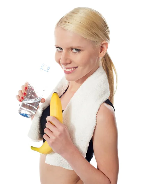 Fitness menina segurando garrafa de água e banana — Fotografia de Stock