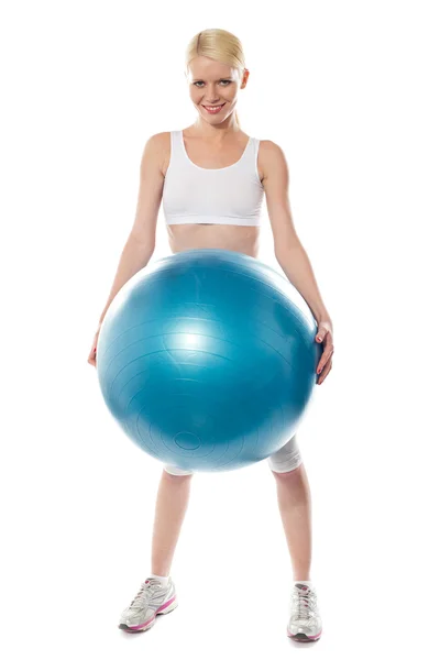 Улыбающаяся спортсменка держит большой синий мяч — стоковое фото