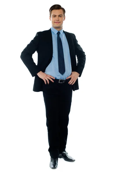 Ganzkörperansicht eines jungen Geschäftsmannes, der mit den Händen auf seiner Taille posiert — Stockfoto