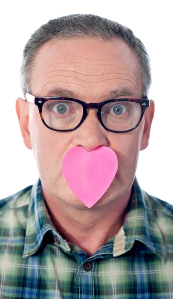 Surpreendido homem envelhecido com papel coração sobre sua boca — Fotografia de Stock