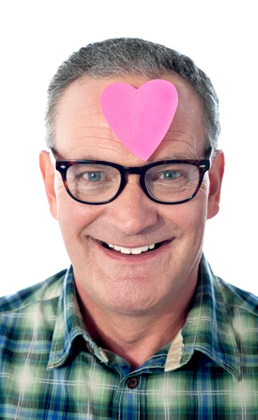 Handsome senior man with paper heart on his forehead — Stock Photo, Image