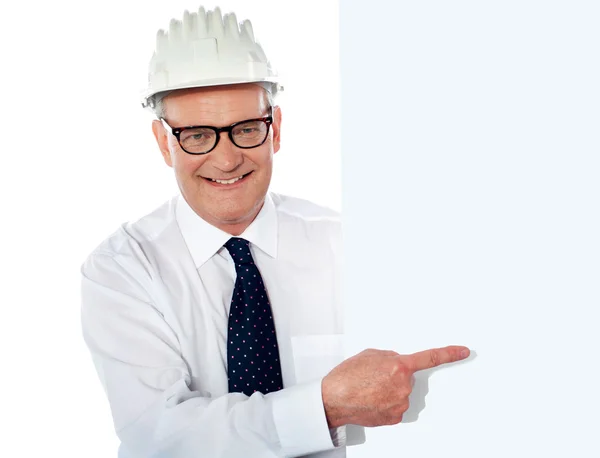 Homem sênior em capacete de construção branco segurando cartaz — Fotografia de Stock