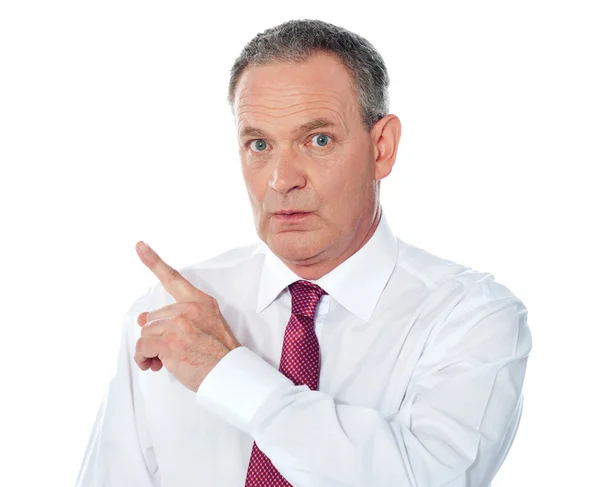 Portrait of senior businessman pointing backwards — Zdjęcie stockowe