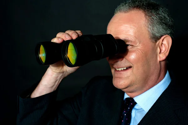 Aged executive monitoring through binoculars — Stock Photo, Image