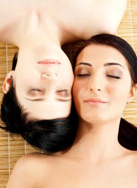 Massage of two beautiful females in spa salon clipart