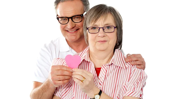 Matured smiling couple holding paper heart — Stock Photo, Image