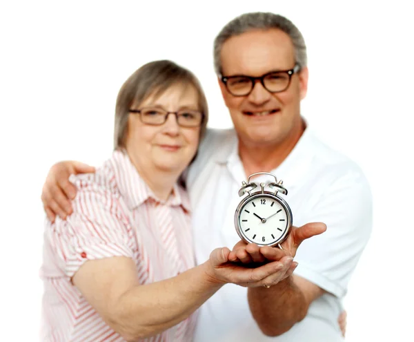 Aged couple with alarm clock on plam — Stock Photo, Image