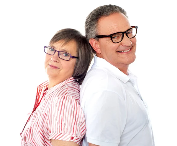 Retrato de una sonriente pareja de ancianos posando espalda con espalda —  Fotos de Stock