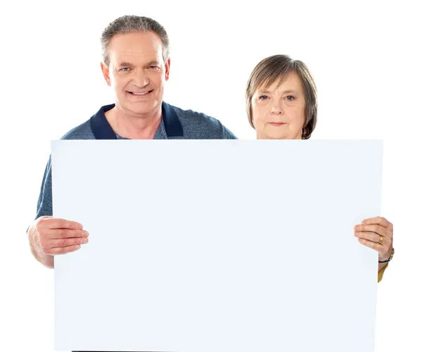 Smiling aged couple displaying blank banner — Stock Photo, Image