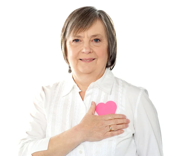 Mogen kvinna med hennes papper hjärta nära kroppen — Stockfoto