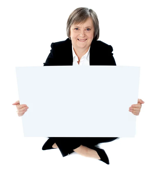 Señora corporativa sentada en el piso con una cartelera en blanco — Foto de Stock