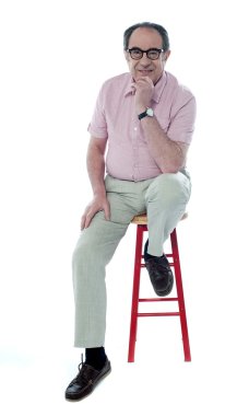 Confident senior man resting on stool clipart