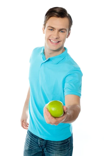 Dobře vypadající zdravý chlapík nabízející zelené jablko — Stock fotografie
