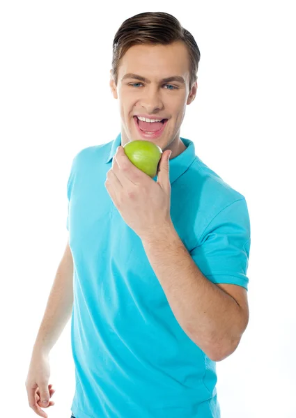 Handsome young caucasian biting an apple — Stock Photo, Image