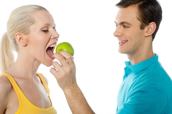 年轻小伙子让她吃一个苹果的女朋友 — 图库照片
