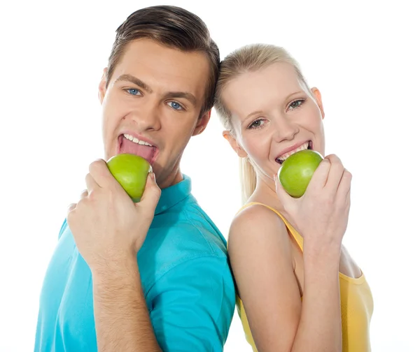 Молодая пара позирует спиной к спине с зелеными яблоками — стоковое фото