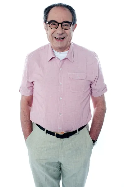 Uśmiechający się dorywczo starszy człowiek z rękami w kieszeni — Zdjęcie stockowe