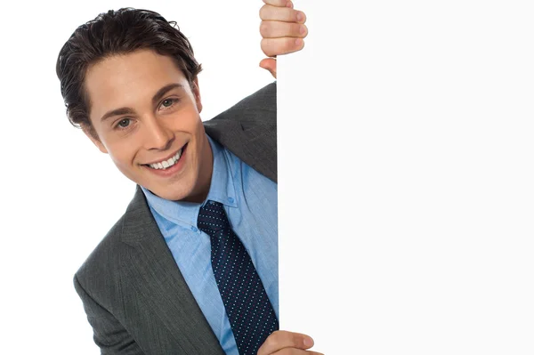 Empresário espreitando atrás de um quadro branco — Fotografia de Stock