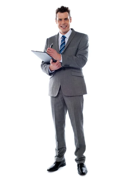 Sonriente hombre de negocios escribiendo en el portapapeles — Foto de Stock