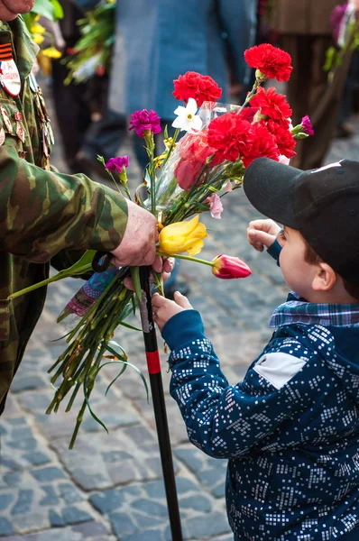 Мальчик дарит цветы ветерану — стоковое фото