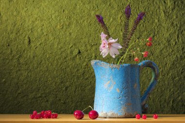 Still life with a can with flowers, cherries and red ber clipart